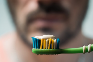 Toothbrush with toothpaste. Blurred male face in the background