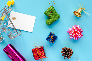 Xmas ornaments with blank credit chip card and mini shopping cart on blue background for Christmas day and holidays concept