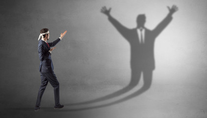 Fototapeta premium Businessman with boxing gloves fighting with disarmed businessman shadow 