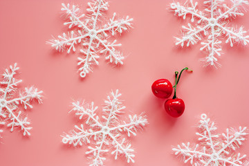 Xmas snowflake with fake red cherry ornaments and decoration on pink background for Christmas day and holidays concept