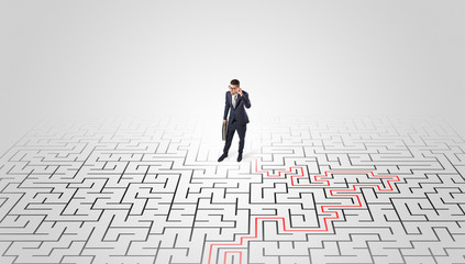 Young entrepreneur standing in a middle of a labyrinth with the solution
