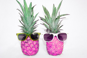 Two pink pineapple in sunglasses on a white background. Bright colours.
