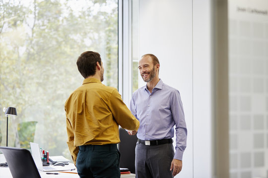 Advisor Shaking Hands With Customer In Office
