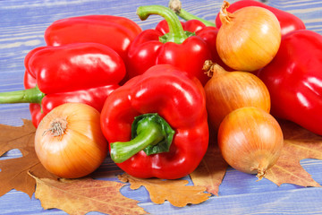 Onions and peppers with autumnal leaves on boards, healthy diet, nutrition and seasonal concept