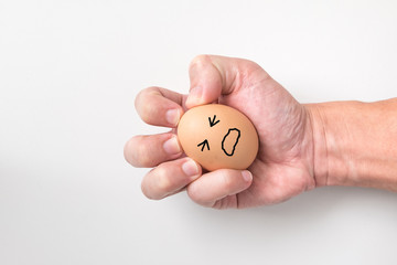 Hand squeeze egg with painful face on white background for emotional concept