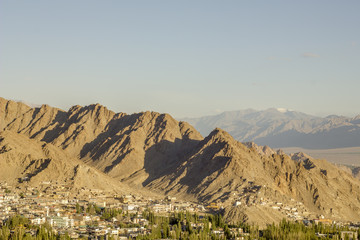 city with forest in a mountain valley and snow peaks