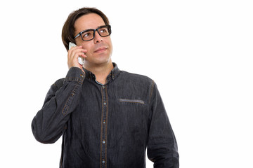 Fototapeta premium Studio shot of young Persian man talking on mobile phone while t