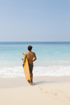 Young man with surfboard stading on the beach