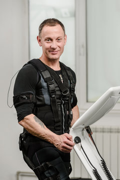 Portrait of athletic man in EMS suit near electro muscle stimulation machine