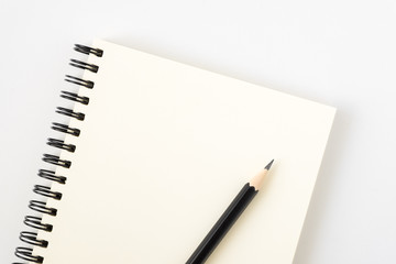 Top view of open spiral blank notebook with pencil on white desk background