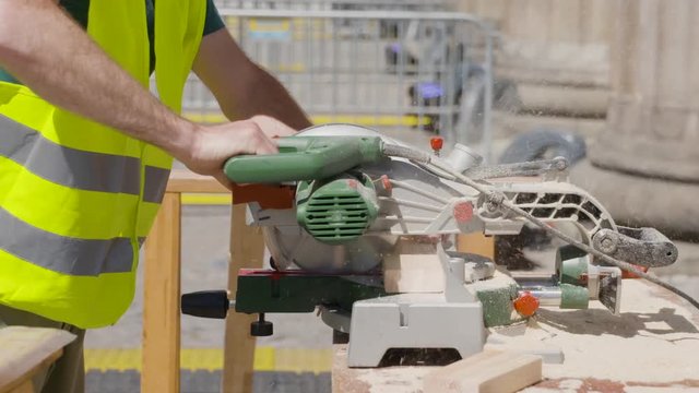 Worker cuts a piece of wood with a buzzsaw.