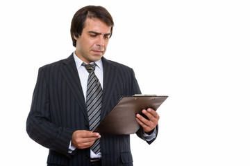 Studio shot of young Persian businessman reading on clipboard