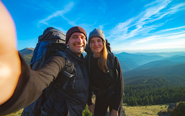The happy couple taking a selfie on the mountain background