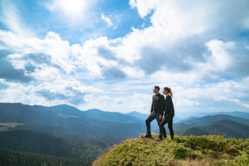 The happy couple standing on the mountain with a picturesque cloudscape