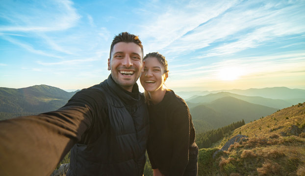 The attractive man and a woman taking a selfie on the mountain background
