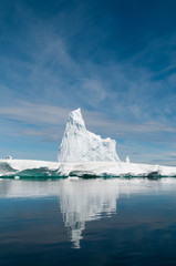 Tall, weathered iceberg reflected on glassy water, Antarctic Peninsula