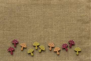 Bordüre aus bunten Holzpilzen auf Hintergrund aus Jute