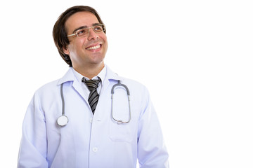 Studio shot of young happy Persian man doctor smiling while thin