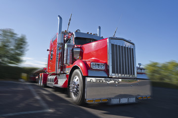 Red classic big rig semi truck with lot of chrome accessories with flat bed semi trailer stand on...