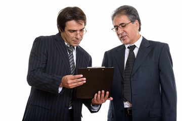 Young Persian businessman reading on clipboard together with sen © Ranta Images
