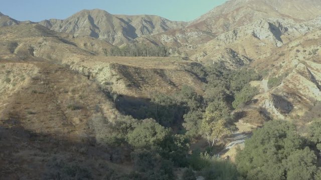Flying around an abandoned metal water tower in a grassy hilly landscape.