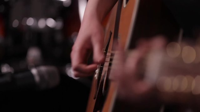 Travelling close up shot of guitarist's hands plays acoustic guitar