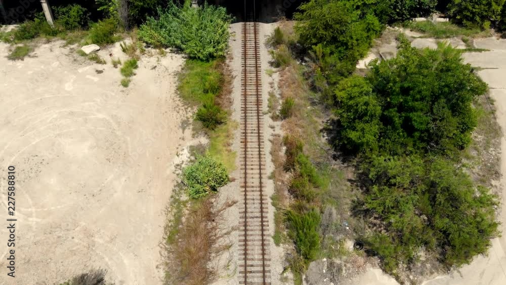 Poster a heighted drone shot, with combined dolly and upward pedestal motion, capturing railway tracks with