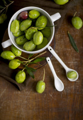 green olives, olive branch and olive oil on a dark wooden board