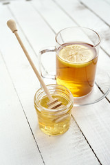 glass with honey and delicious lemon tea on an old white wooden table