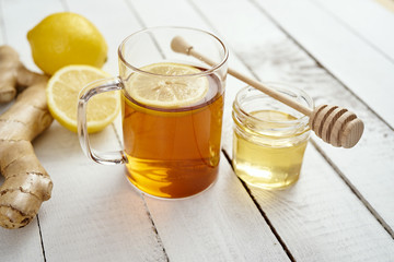 delicious hot tea with lemon on an old white wooden table with ginger and honey