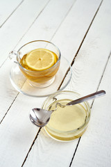 delicious hot tea with lemon and honey on an old white wooden table