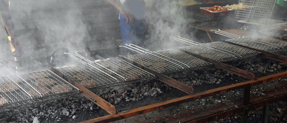 smoke rises from the grids on which beef burgers are cooked