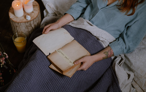 woman reading on bed close to candles