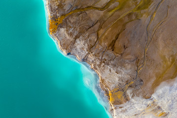 Top down view on rich mineral waste flow from power plant to emerald lake.