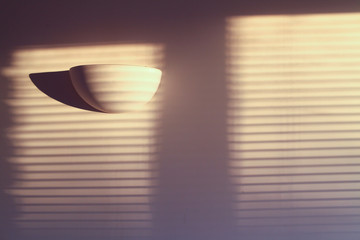Interior scene of shadows of blinds cast against a wall