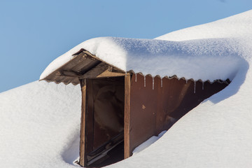 Snow on the roof of the house in winter