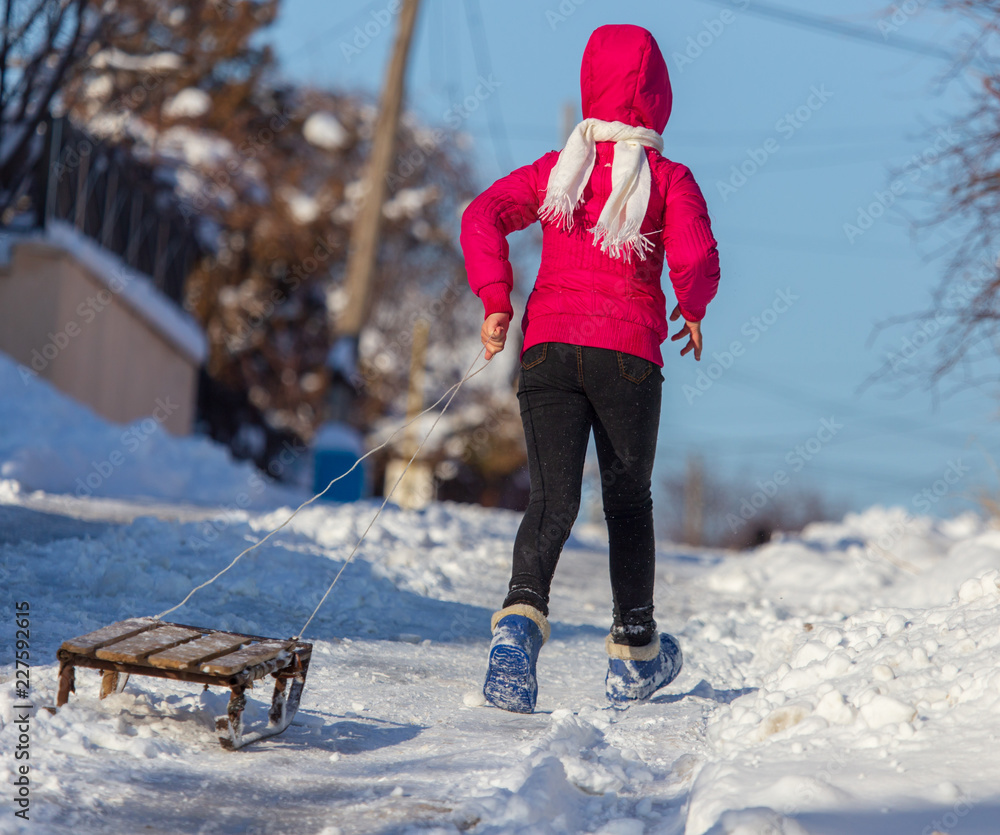 Wall mural girl with sled in the snow in winter