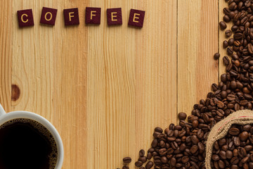 cup of coffee with beans on wooden background