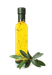 Glass bottle of oil and olive leaves on white background