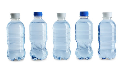 Row of different plastic bottles with water on white background