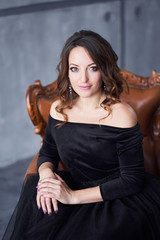 Beautiful girl with makeup and hairdo in a black dress