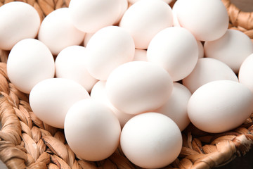 Pile of raw white chicken eggs in basket