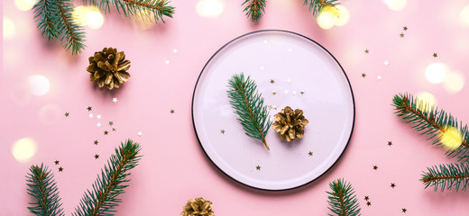 Christmas festive table setting. White plate andbokeh lights on pink background, banner format