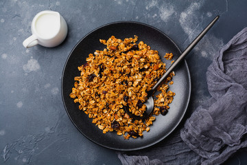 Oatmeal granola with yoghurt, fresh strawberries and banana, chia seeds, sunflower and honey in black ceramic plate on dark background. Top view.