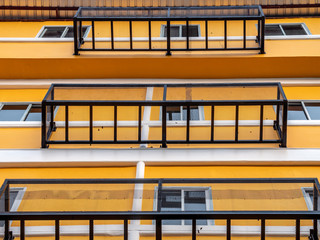 Illuminated image of building with low angle view, exterior design by make iron grate outside building. Level of building with look up view in sunny day. Fire exit design by iron grate outside windows