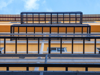 Illuminated image of building with low angle view, exterior design by make iron grate outside building. Level of building with look up view in sunny day. Fire exit design by iron grate outside windows