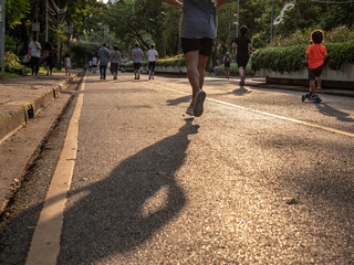Selective focused on foreground at pathway with emotion blurred background. Rear view of people who are walking and running in public park. Low selection view of the way forward.