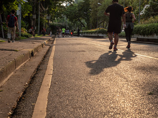 Selective focused on foreground at pathway with emotion blurred background. Rear view of people who are walking and running in public park. Low selection view of the way forward.