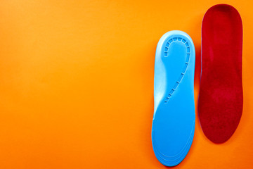 Foot support and healthy feet concept with orthopedic shoe insoles isolated on orange background with copy space