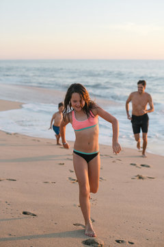 Energetic dad playing with kids on the beach at sunset